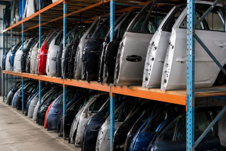 Rows of used car doors organised on warehouse storage racks at an automotive recycling facility.