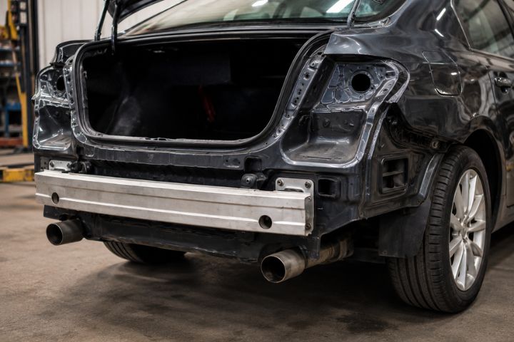 Passenger car with the rear bumper removed, showing the rear reinforcement bar before replacement bumper installation.