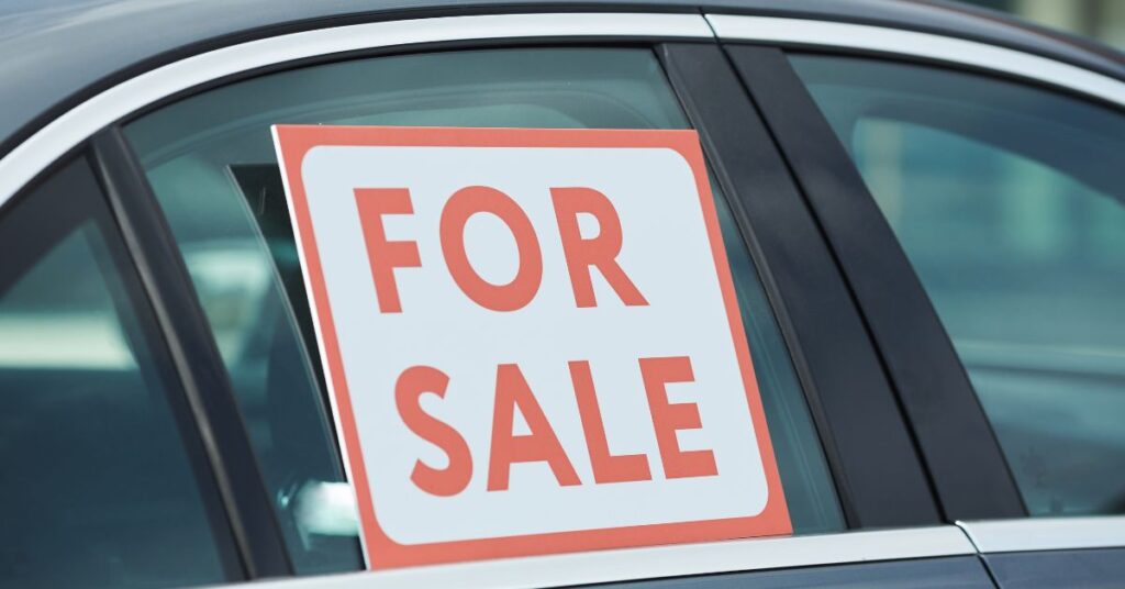 For sale sign displayed in the side window of a used car.